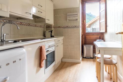 a kitchen with white appliances and a table and a window at Casa Pelaire Biescas in Biescas