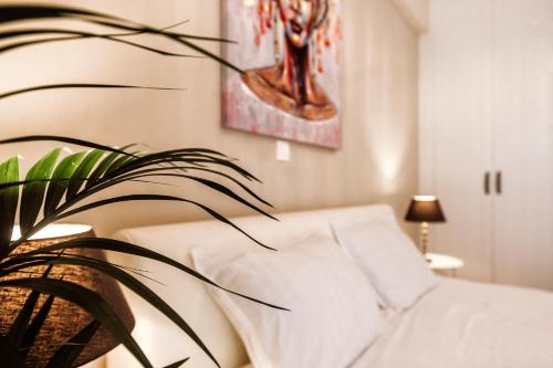 a bedroom with a white bed and a plant at Kentia Fine Living Apartment in (( Agía Eleoúsa ))
