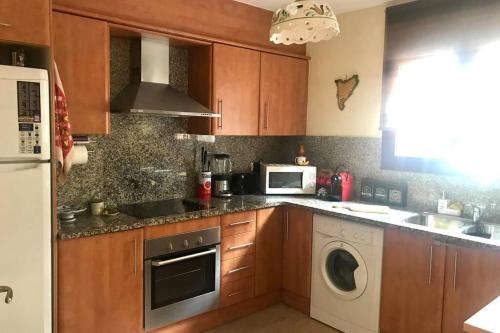a kitchen with wooden cabinets and a washer and dryer at Apartament amb parking privat a St Joan de les Abadesses in Sant Joan de les Abadesses