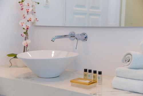 a bathroom with a sink and a mirror and towels at Dionysos Luxury Hotel Mykonos in Ornos