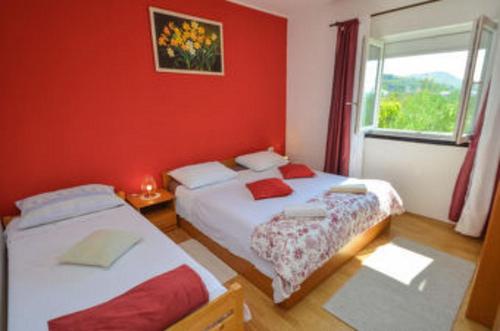 two beds in a room with red walls and a window at Apartmens Zara in Šibenik