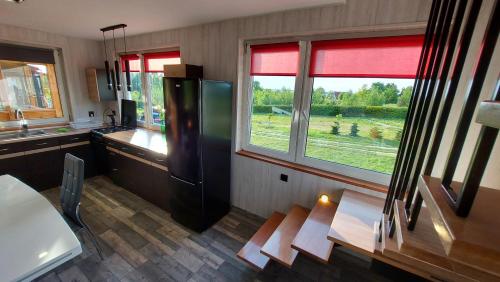 a kitchen with a refrigerator and a large window at Agrodomki-OKEJ Dom Belweder in Gardna Wielka