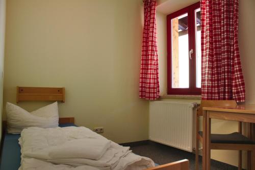 a bedroom with a bed and a desk and a window at ALPEN EXPERIENCE - CVJM Aktivzentrum Hintersee, Jugendgästehaus in Ramsau