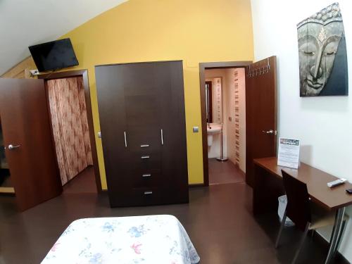 a room with a bed and a desk and a room with a table at Hostal Nirvana in Ponferrada