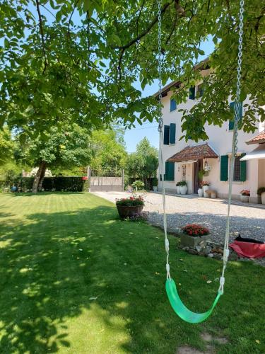 un columpio verde colgando de un árbol en un patio en Casa sulla roggia en Lumignacco