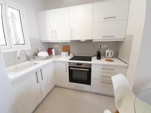 a white kitchen with white cabinets and a sink at Aria, Maisonette in Glyfada Beach in Glyfada