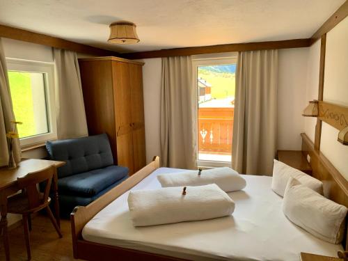 a bedroom with a bed and a chair and a window at APART Kirschner in Sankt Leonhard im Pitztal