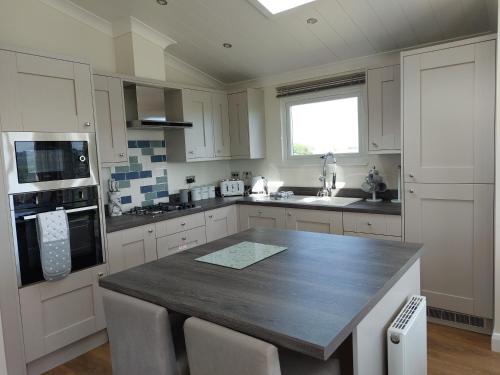 a kitchen with a large wooden table with chairs at Luxury family Beechwood lodge with hot tub in Lochwinnoch