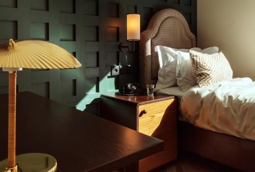 a bedroom with a bed and a desk with a lamp at The Hoxton, Rome in Rome
