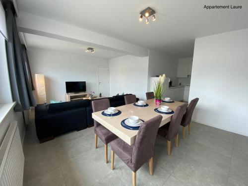 a dining room with a table and chairs and a couch at Residentie Duinenzucht - Appartement Laure I Studio Lynne in Bredene