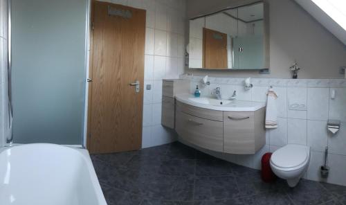 bagno con lavandino, servizi igienici e specchio di Ferienwohnnung Kathrin a Wremen