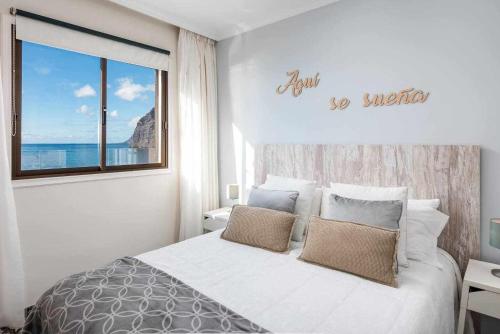 a white bedroom with a bed and a window at Los Gigantes Paradise in Acantilado de los Gigantes