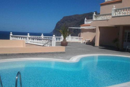 a swimming pool in front of a house with the ocean at Los Gigantes Paradise in Acantilado de los Gigantes