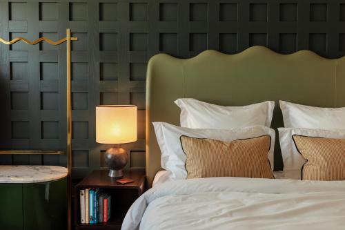 a bedroom with a white bed with a green headboard at The Hoxton, Rome in Rome