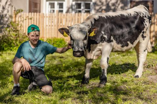a man is petting a black and white cow at Bauernhof Oberlöffele in Jenig