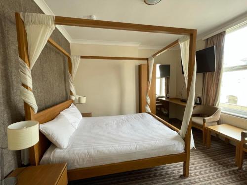 a bedroom with a canopy bed and a desk at Ashley Victoria in Blackpool