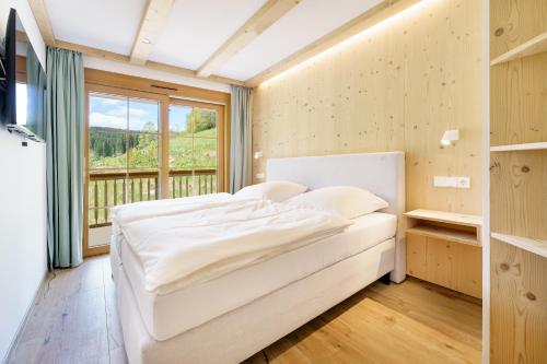 um quarto com uma cama branca e uma janela em SCHWARZENBACH - Apartments & Rooftop Pool em Feldberg