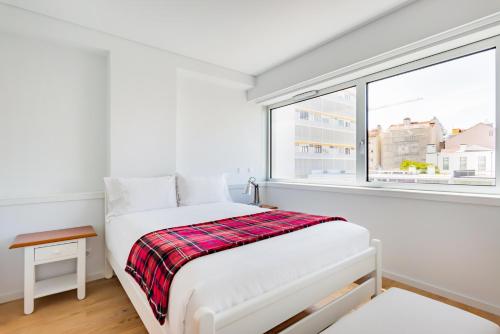 um quarto branco com uma cama e uma janela em Estrela Modern Flat @ Infante Santo em Lisboa