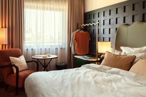 a hotel room with a bed and a chair and a window at The Hoxton, Rome in Rome
