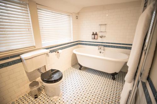 a bathroom with a tub and a toilet and a sink at Tower House Guest House in Oxford
