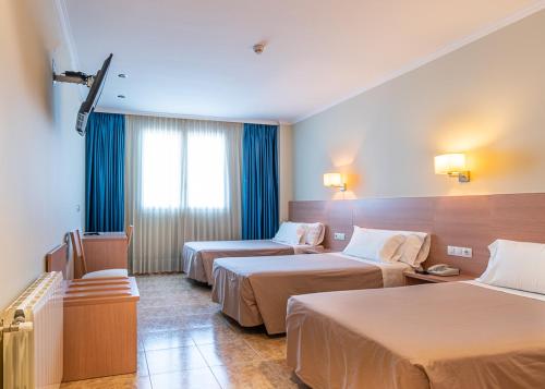 um quarto de hotel com duas camas e uma janela em Hotel Alba em Puçol