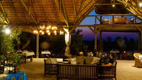 un restaurant avec des personnes assises sous un toit dans l'établissement Lianshulu Lodge, à Kongola