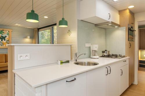 uma cozinha com armários brancos e um lavatório em Center Parcs Erperheide em Peer