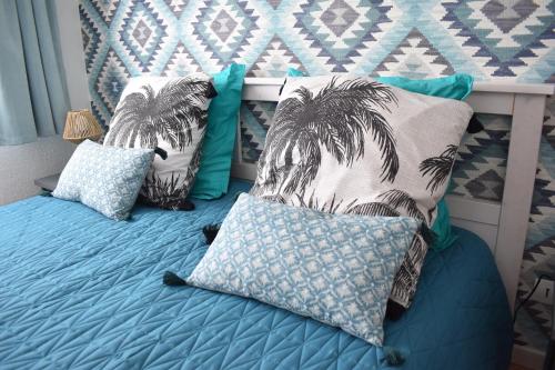 - un lit avec des oreillers bleus et des palmiers dans l'établissement Appartement climatisé look industriel avec piscine à la plage, à La Londe-les-Maures