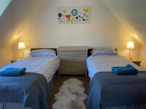 a bedroom with two beds and a dresser at Burnside Cottage on the Blarich Estate in Rogart