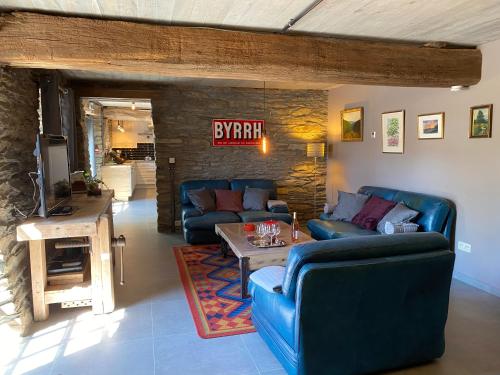 a living room with two blue couches and a table at Le Scailleteux - Gîte de charme clôturé, accès à la rivière in Fauvillers