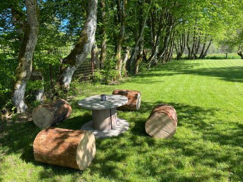 a garden with a table and some rocks and trees at Le Scailleteux - Gîte de charme clôturé, accès à la rivière in Fauvillers