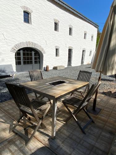 a wooden table with two chairs and an umbrella at Le Scailleteux - Gîte de charme clôturé, accès à la rivière in Fauvillers