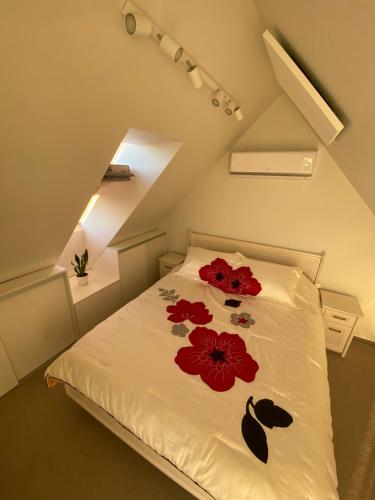 a bedroom with a bed with red flowers on it at Apartamentai Kunigiškėse in Palanga