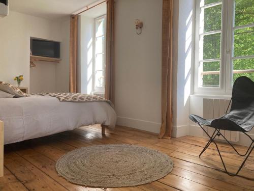 a bedroom with a bed and a chair and windows at Chambres d hôtes du Moulin à papier in Saint-Brieuc
