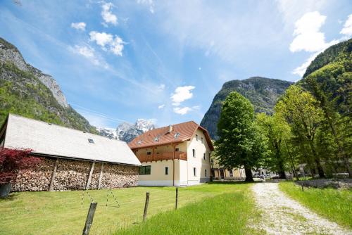 a house in a field with mountains in the background at Apartments and rooms Nataša 1 in Trenta
