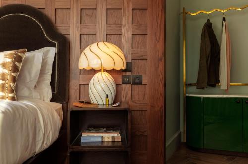 a lamp on a night stand next to a bed at The Hoxton, Rome in Rome