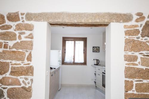 a kitchen with white walls and a stone wall at La Piazzetta in Lotzorai