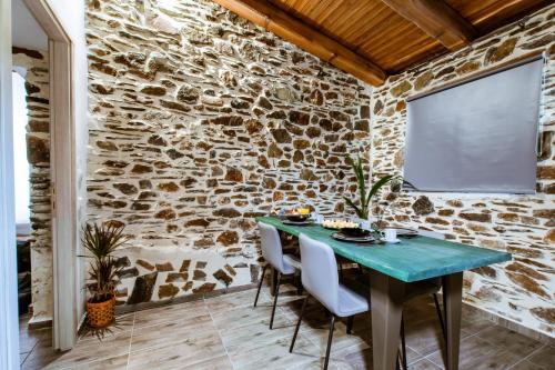 a stone walled dining room with a blue table and chairs at Traditional Apartments Elafos in Loúkhiou
