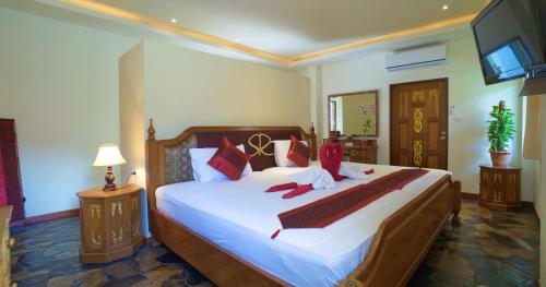 利巴诺伊暹罗原住精品度假酒店的卧室里有一张白色的大床，上面有红色的枕头