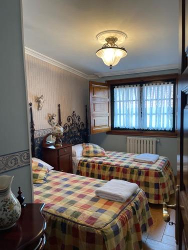 a bedroom with two beds and a window at Casita Piñeiro estilo rural in Boiro