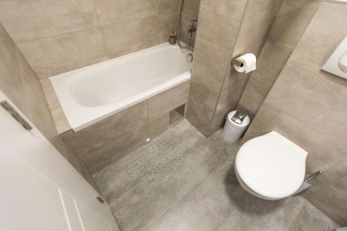 a bathroom with a toilet and a tub and a sink at MB Apartment in Subotica