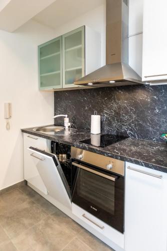 a kitchen with white cabinets and a black counter top at MB Apartment in Subotica