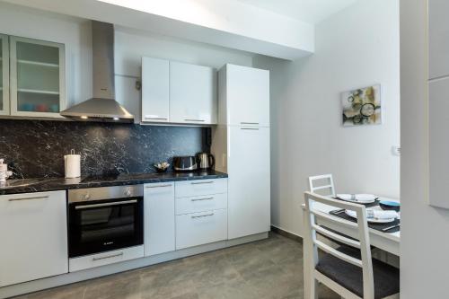 a kitchen with white cabinets and a stove top oven at MB Apartment in Subotica
