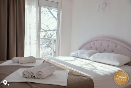 a bed with two towels on it with a window at Resort Stikovic in Dobra Voda