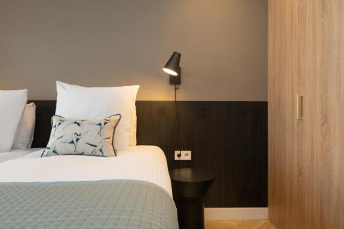 een slaapkamer met een bed met een blauw kussen en een lamp bij BizStay Maurits in Den Haag