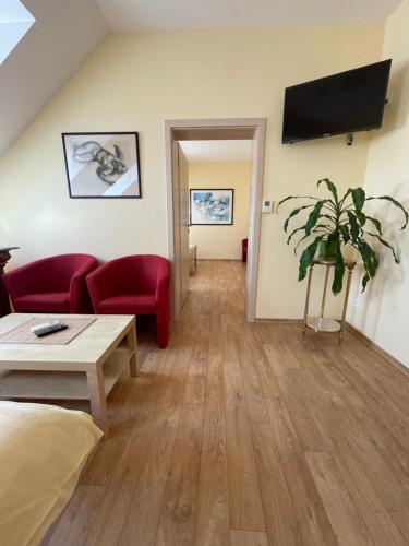a living room with a couch and a tv on the wall at Penzion U Bohuša in Lednice