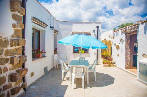 a table and chairs with a blue umbrella on a patio at La Piazzetta in Lotzorai