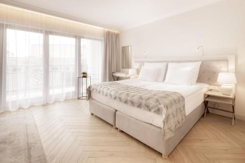 a white bedroom with a large bed and a large window at Maritime Residence in Międzyzdroje