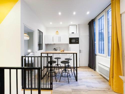 une cuisine avec un comptoir et des tabourets dans une pièce dans l'établissement LA GRACIEUSE - MILORA INN - Central Paris, à Paris