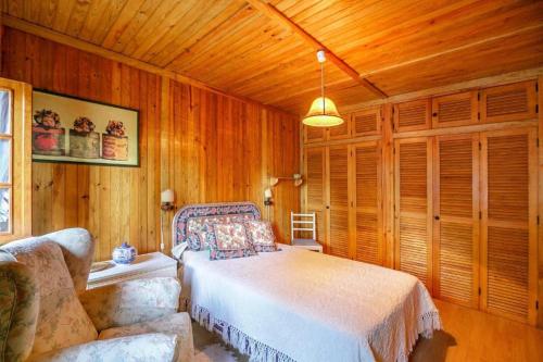een slaapkamer met een bed, een bank en houten wanden bij LovelyStay - Toca dos Coelhos in Marco de Canavezes